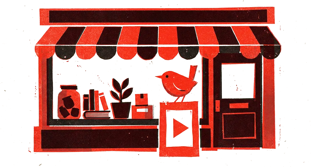A small shop with a striped awning, a red video frame hanging in its window and a wren perched on top of it